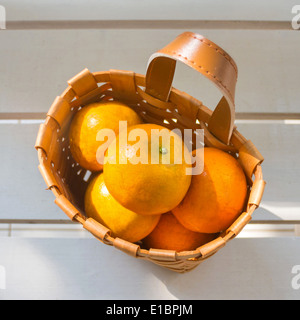 Les oranges dans le panier sur la chaise blanche. Banque D'Images