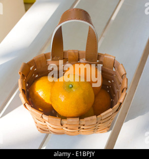 Les oranges dans le panier sur la chaise blanche. Banque D'Images