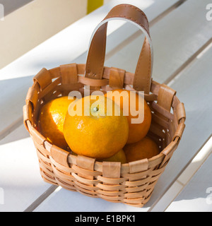 Les oranges dans le panier sur la chaise blanche. Banque D'Images