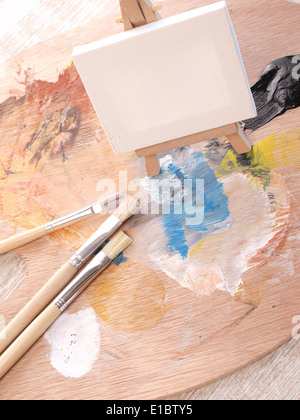 Palette de peinture avec des pinceaux et une petite toile Banque D'Images