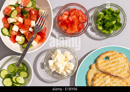 Préparer un plat d'une salade méditerranéenne avec des ingrédients frais dans des bols avec tomates, concombres, fromage feta et Bell Banque D'Images