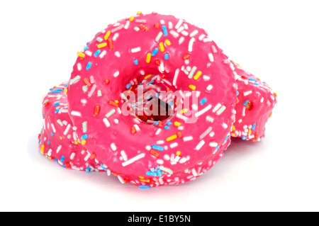 Un tas de donuts recouverts d'un glaçage rose et saupoudre de différentes couleurs sur un fond blanc Banque D'Images