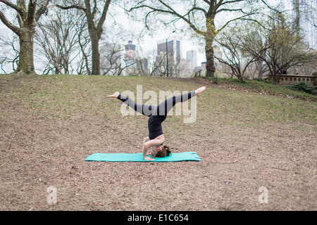 Une jeune femme à Central Park, dans un justaucorps noir et leggings, faisant du yoga. Banque D'Images