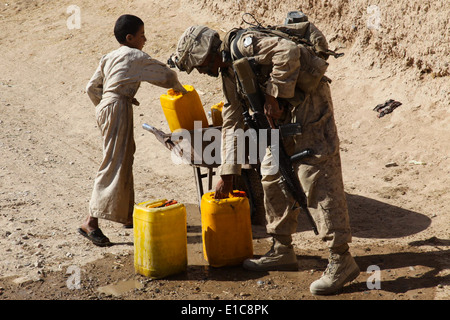 Le Corps des Marines des États-Unis. Kevin Choeun aide un garçon afghan recharger sa brouette avec de l'eau à lors d'une patrouille dans le Naw Banque D'Images