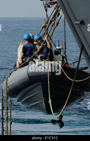 Les marins américains dans un canot pneumatique à coque rigide se préparent à être descendu dans l'eau au cours des opérations à bord de petits bateaux le aircr Banque D'Images