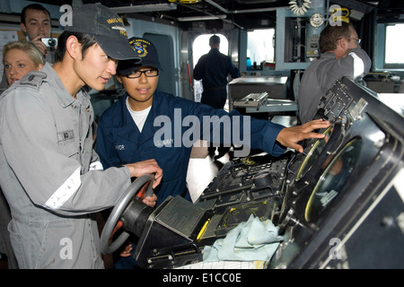 La Marine américaine d'équipage ?s'accoupler Heather Seaman Connor explique les fonctions de la barre à bord du destroyer lance-missiles USS McCampb Banque D'Images