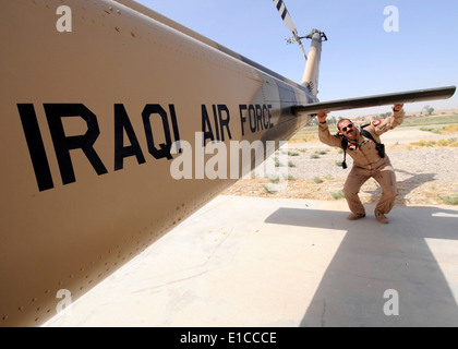 Un pilote de l'armée de l'air iraquienne preflight effectue une vérification sur un hélicoptère Huey UH-1H sur la base d'opération avancée Diamondback à Mossoul, Banque D'Images