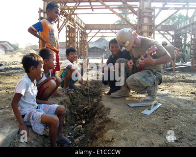 La Marine américaine Builder 3 classe Seth Blair, de la Naval Construction Battalion 40 Mobile, joue de la guitare pour les enfants pendant un moteur Banque D'Images