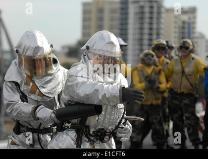 Les marins américains affectés au ministère de l'air ?s l'accident et l'équipe de récupération d'une simulation de lutte contre l'incendie classe bravo sur le pont de vol de l'a Banque D'Images