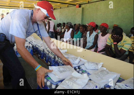 Bob Brewer, volontaire de convoi de l'espoir, distribue de la nourriture et l'eau à une mission d'espoir complexe dans Source Matelas, Haïti, Banque D'Images