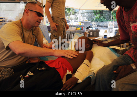 Le capitaine de l'armée américaine Buddy Davis tend à un garçon haïtien à Port-au-Prince, Haïti, 4 février 2010. Le ministère de la défense et de l'U. Banque D'Images