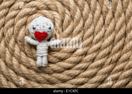 Valentine poupée faite à partir de fil blanc avec un coeur au lieu de bouche , couché sur un fond corde Banque D'Images