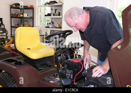 L'homme travaillant sur le moteur du tracteur en garage sur une maison Banque D'Images