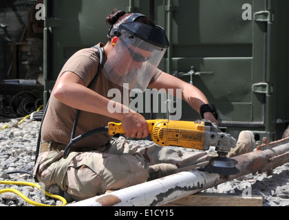 U.S. Navy Steel Worker 1re classe Jeannie Cooper, de la Naval Construction Battalion Mobile 133, broie la rouille et la peinture d'un fla Banque D'Images