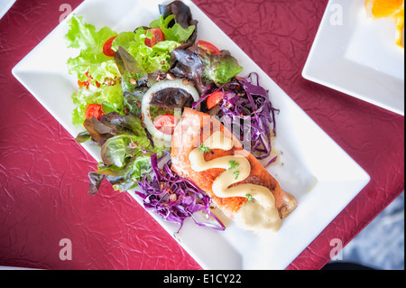 Pavé de saumon grillé croustillant avec de la salade sur un plat blanc Banque D'Images