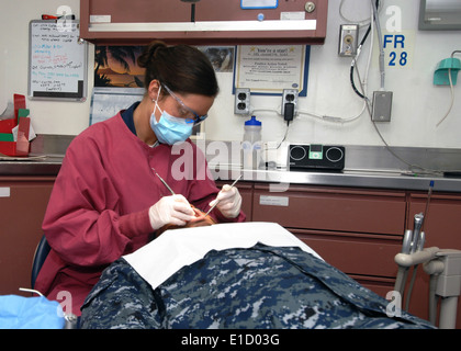 L'Hôpital de la Marine américaine 3e classe Corpsman Emily Brown effectue un nettoyage dentaire de routine sur un marin à bord du porte-avions-nous Banque D'Images