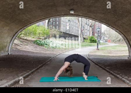 Une jeune femme à Central Park, dans un justaucorps noir et leggings, faisant du yoga. Banque D'Images
