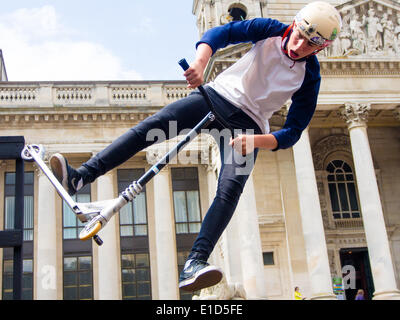 Un scooter rider effectue une cascade aérienne en face de la Portsmouth Guildhall au cours de la rue de Portsmouth en 2014 Banque D'Images