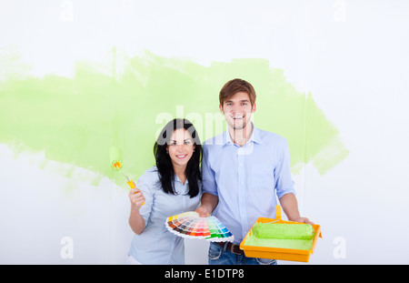 Jeune couple mur à la maison de peinture Banque D'Images