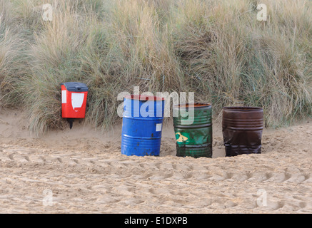 Vide rouge, vert et bleu le tambour à huile poubelles sur la plage en face de l'ammophile couverts de dunes. Hunstanton, Norfolk, Royaume-Uni. Banque D'Images