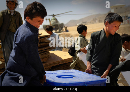 De jeunes Afghans aider à décharger du matériel de scrutin un hélicoptère Mi-17 dans Jaghuri, Afghanistan, le 16 septembre 2010. Les bulletins sont fo Banque D'Images