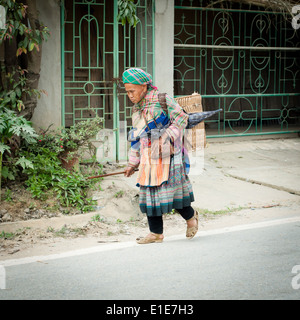 Une vieille femme marche Flower Hmong accueil dans le marché du dimanche de Bac Ha Bac Ha, province de Lao Cai, Vietnam. Banque D'Images