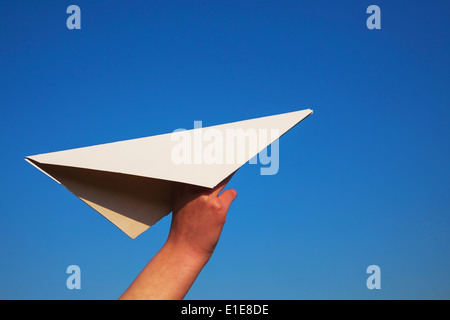 Hand holding paper plane contre le ciel bleu Banque D'Images