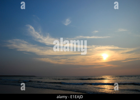 Soleil derrière les nuages orange hue jette pendant le coucher du soleil sur la mer Banque D'Images