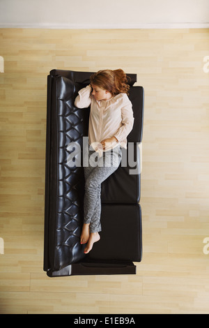 Top View of young woman lying on a couch de prendre une sieste. Les femmes de race blanche de dormir sur un canapé à son appartement. Banque D'Images