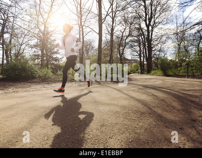 Jeune femme en bonne santé jogging en parc. Modèle féminin de remise en forme d'exécution en forêt. Modèle de remise en forme du Caucase l'exercice en plein air. Banque D'Images