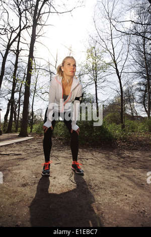 Jeune coureuse d'arrêter pour se reposer. Femme de remise en forme en faisant une pause d'une formation à l'extérieur dans un parc. Banque D'Images