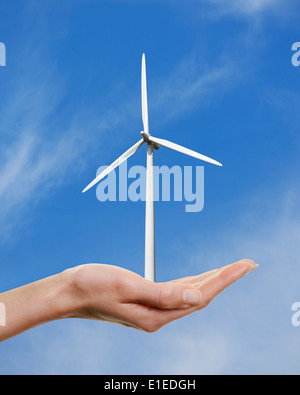 La main de femme tenant une éolienne contre un ciel bleu. Banque D'Images