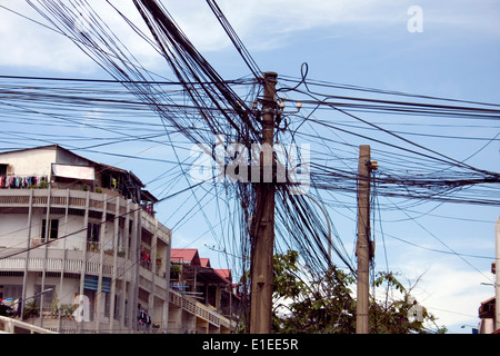 Lignes électriques et téléphoniques font partie de l'infrastructure au-dessus d'une rue de ville de Phnom Penh, Cambodge. Banque D'Images