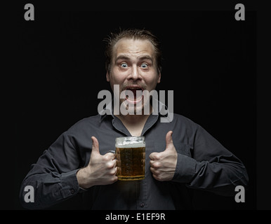 L'homme satisfait avec de la bière sur un fond sombre. Studio de photographie. Banque D'Images