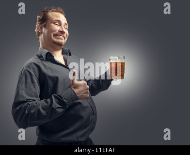 L'homme satisfait avec de la bière sur un fond sombre. Studio de photographie. Banque D'Images