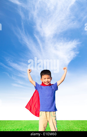 Petit garçon heureux et super-héros imitent les bras ouverts avec ciel bleu Banque D'Images