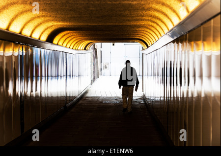 La silhouette d'un homme marchant à travers un passage souterrain pour piétons. Banque D'Images