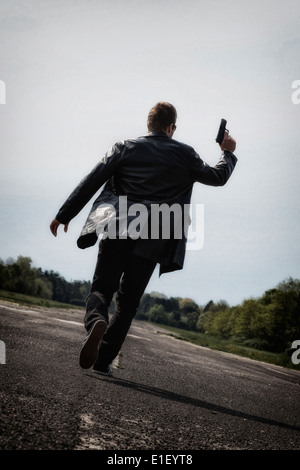 Un homme qui court sur une rue avec une arme à feu Banque D'Images