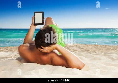 Man relaxing on beach lecture e-book Banque D'Images