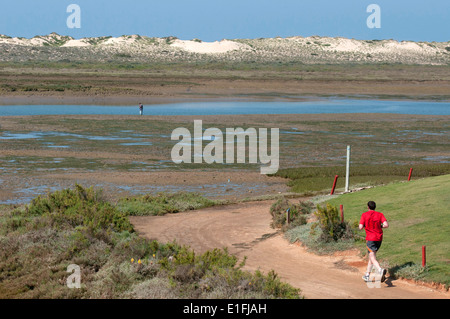 Homme qui court le long du chemin qui longe la réserve naturelle de Ria Formosa en Quinta do Lado au Portugal. Banque D'Images