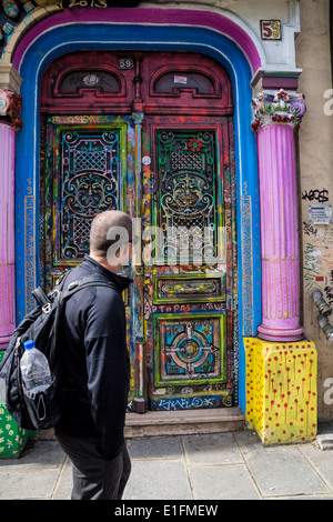 Paris, France. Un homme passe devant une porte de couleur sur une rue parisienne. Banque D'Images