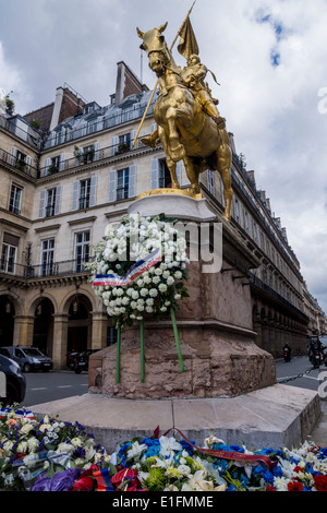 Rue de Rivoli, Paris, France. Des guirlandes de fleurs sur la statue en bronze de Jeanne d'Arc. Banque D'Images