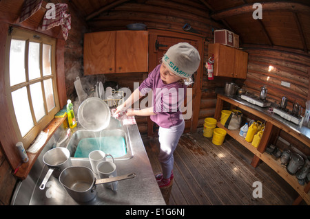 Une jeune fille à faire la vaisselle dans le refuge Elizabeth Parker, lac O'Hara, le parc national Yoho, Field, Colombie-Britannique, Canada. Banque D'Images