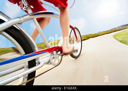 Un angle unique d'un homme monté sur son beach cruiser vers le bas de la piste cyclable en short de bain et des sandales. Ce rig shot donne un sens de la s Banque D'Images