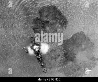Photographie d'un navire marchand japonais 7 000 tonnes après un coup direct par Indian Air Task Forces près de Rangoon, en Inde. Les petits bateaux remplis de membres de l'équipage peut être vu. Les eaux sont couvertes de marée noire. Datée 1943 Banque D'Images