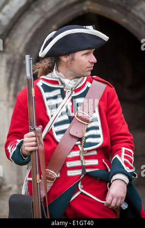 Un soldat vêtu de l'armée anglaise traditionnelle du xviie siècle portant un uniforme Redcoat mousquet à silex en dehors d'une entrée du château Banque D'Images