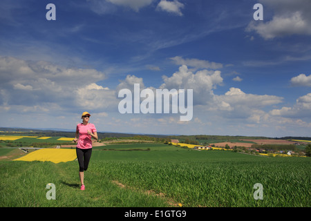 Woman jogging à travers champs au printemps Banque D'Images