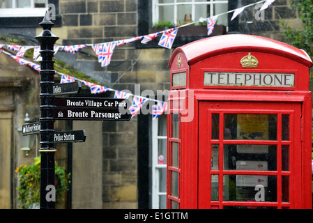 Boîte de téléphone rouge et panneau touristique dans la pluie à Haworth, West Yorkshire Banque D'Images