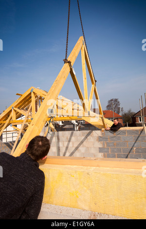 L bâtiment maison, plaçant les hommes fermes de bois faites en usine beling mise en place sur le toit par grue Banque D'Images