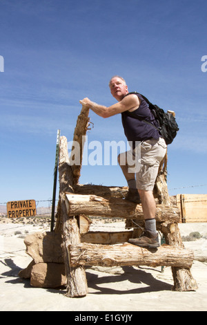 Man climbing over fence pour entrer dans une propriété privée Banque D'Images